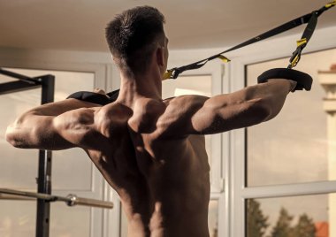 Sporcu, atlet, kas maço mu egzersiz trx döngüler ile arka plan, pencereye yakın. Adam çıplak gövde ve geri içinde jimnastik salonu kas eğitim, trx tadını çıkarın. Spor ve spor salonu konsept