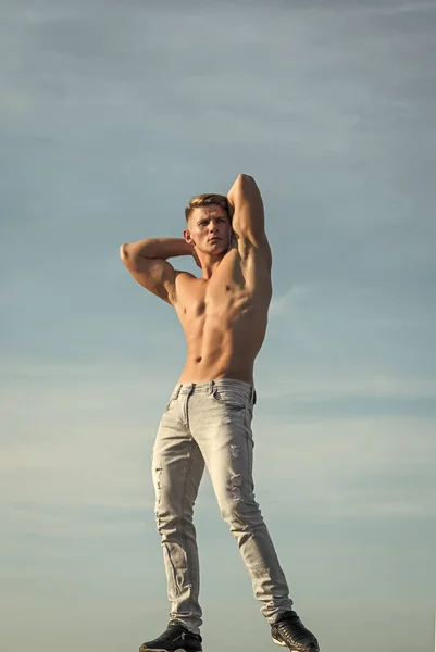 Sportman vertonen sterke lichaam jeans op blauwe hemel — Stockfoto