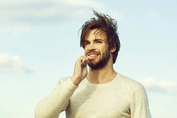 Homme heureux brosse les dents avec du dentifrice sur ciel bleu, metrosexual — Photo