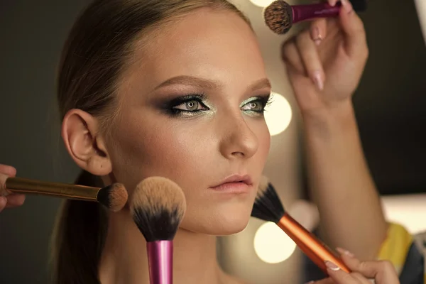 Young woman has brushes around face makeup — Stock Photo, Image