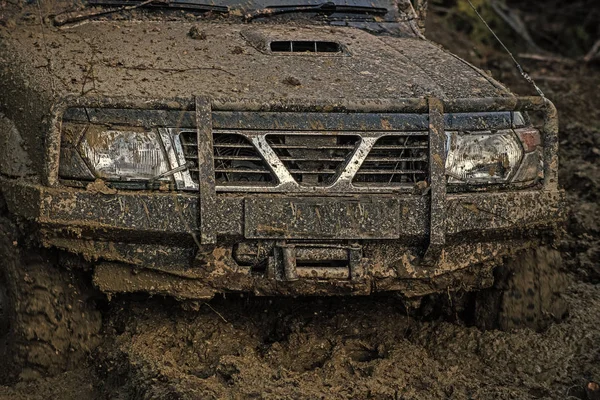 Koyu arka plan üzerinde çamur içinde sıkışmış offroad araba parçası. — Stok fotoğraf