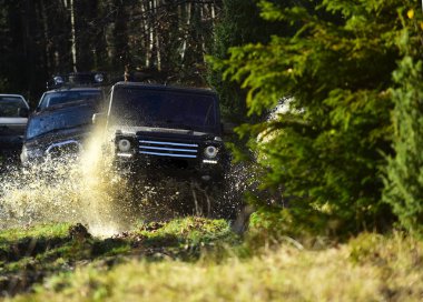 Su birikintisi sıçrama ile geçiş Jip ya da spor yeni araç. Offroad yarış Sonbahar Doğa arka plan üzerinde. Toplanma, rekabet ve dört tekerlekli sürücü kavram. Motor sonbahar ormanda yarış.