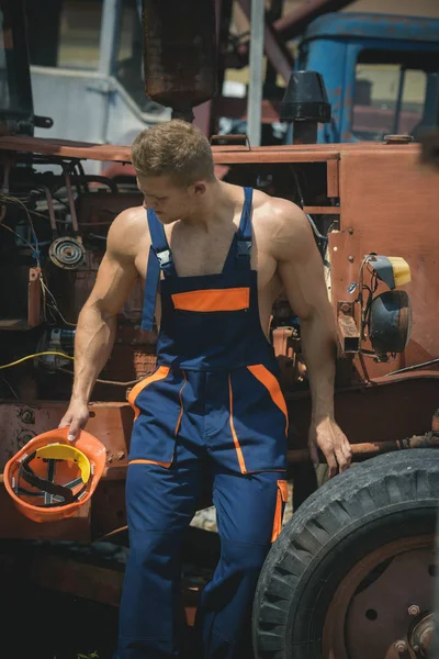 Concepto de artesano. El artesano descansa en la cabina del tractor. Artesano fuerte en uniforme de trabajo en la máquina de construcción pesada. Artesano en retroexcavadora —  Fotos de Stock