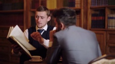 Adam meslektaşı kitapta bir makale gösterir. Araştırmacılar bir kütüphane kitap okumak. Öğrenme kavramı.