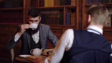 İki saygın ve akıllı adam kütüphanede iletişim. İletişim kavramı. İki adam kahve içmek ve kitaplığa iletişim.