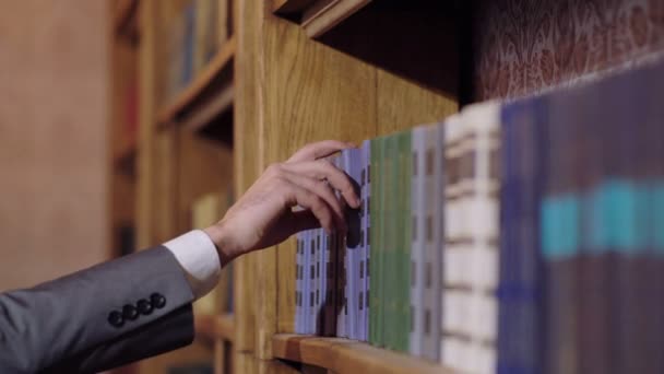 남자는 도서관에 있는 책장에서 책을 당긴 다. 라이브러리 개념. — 비디오
