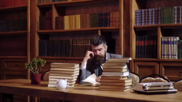 L'uomo barbuto legge un libro in biblioteca. Il concetto di scienza . — Video Stock