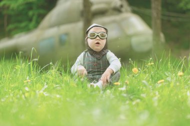 Çocuk pilot kask ve yeşil çim oturan gözlük