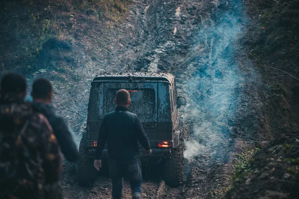 Compañía de tres hombres mira las unidades de SUV con humo . — Foto de Stock