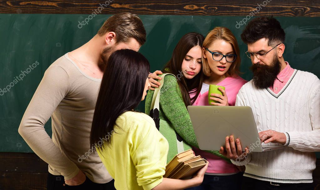 Group of students, groupmates spend time with teacher, lecturer, professor. College and university concept. Students, scientists studying after classes, professor holds laptop, teaches , explaining.