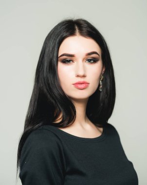 Studio poz uzun siyah saçlı güzel genç kadın. Gri arka plan üzerinde izole esmer dumanlı gözler