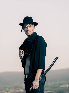 Adam katana kılıcı ve gri gökyüzü üzerinde duran güneş gözlüğü