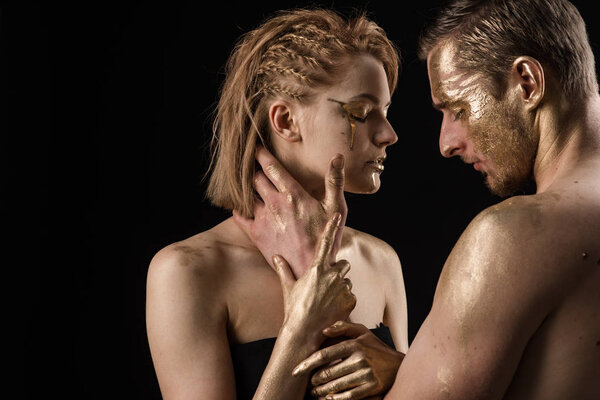 Golden collagen mask and beauty. 24K Gold. Gold spa and skincare treatment. Sexy couple with golden body art makeup isolated on black. Man and woman relations. Erotic games of couple in love.