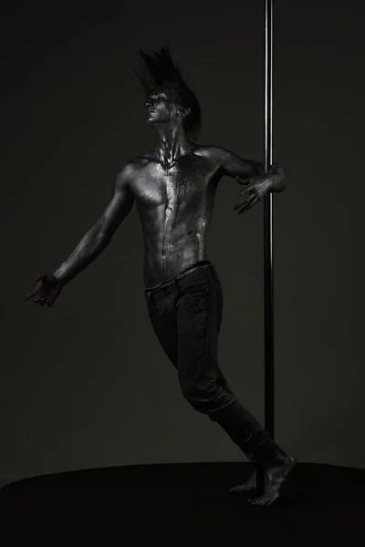 Pole dance sport. Muscular man with silver body art dancing on pylon. Athletic man make acrobatic elements on pylon. Sexy macho with metal skin. Strong dancer workout on pole. Freedom. — Stock Photo, Image