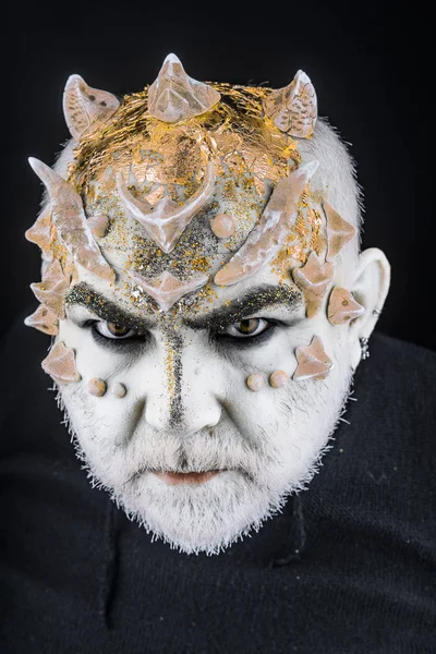 Dikenler veya siğiller, baş yüz pırıltılar ile kaplı, yakın çekim. Uzaylı, iblis büyücü makyaj. Fantezi kavramı. Ciddi yüz, siyah zemin üzerine iblis. Sakallı canavar makyaj ile üst düzey adam.