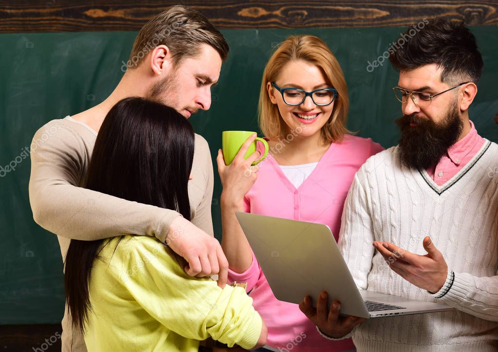 Group of students, groupmates spend time with teacher, lecturer, professor. College and university concept. Students, scientists studying after classes, professor holds laptop, teaches , explaining.