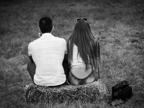 Девушка и мужчина сидят на тюке сена на зеленой траве — стоковое фото