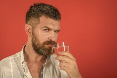 Uzun sakallı adam tutun su bardağı kırmızı zemin üzerine.