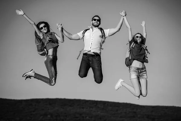 Freunde, glückliche Touristen springen auf Berggipfel bei blauem Himmel — Stockfoto