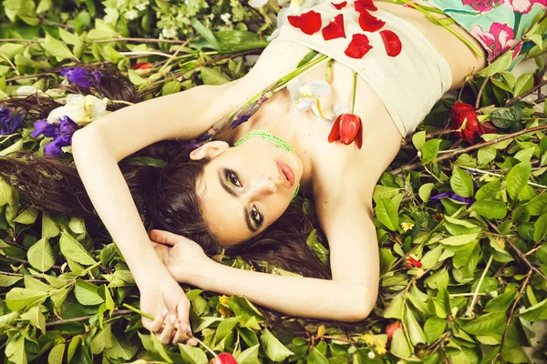 Mujer con maquillaje de moda con flores en hojas verdes — Foto de Stock