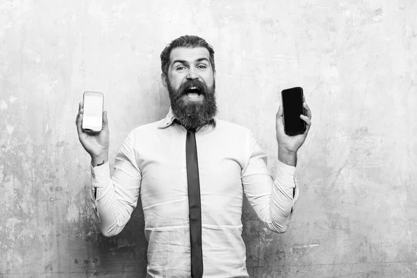 Mies tai hipster vertailla matkapuhelin ja älypuhelin — kuvapankkivalokuva