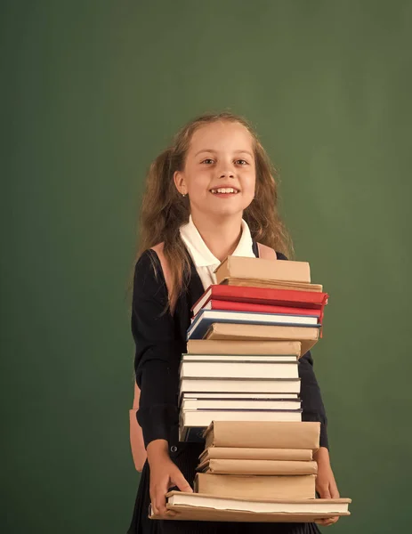 Schülerin mit lächelndem Gesicht hält riesigen Stapel Bücher in der Hand — Stockfoto