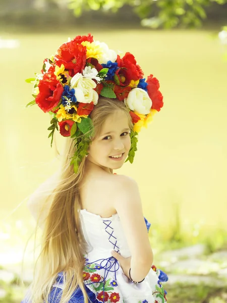 Kleines Mädchen in geblümtem Kleid und Blumenkranz — Stockfoto