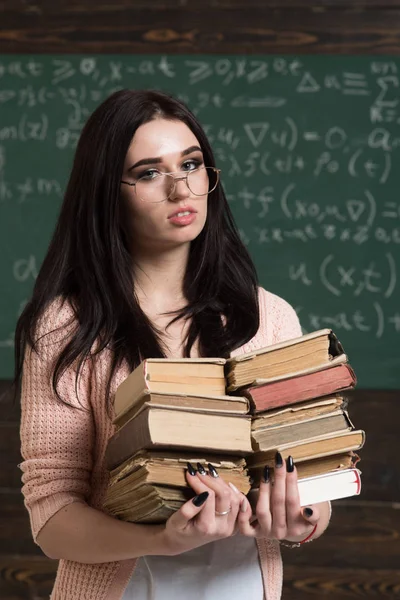 Mooie brunette meisje bedrijf hoopje van boeken in haar handen. Slimme studenten voorbereiden op examens — Stockfoto