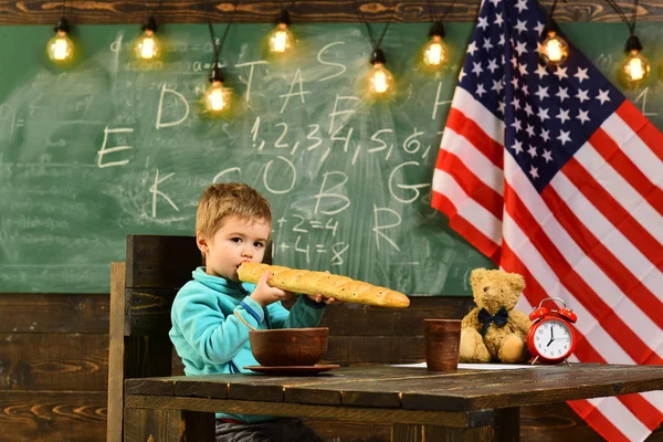 Patriottismo e libertà. Il bambino mangia pane alla bandiera americana al giorno della conoscenza. Ragazzo della scuola a lezione il 4 luglio. Giorno d'indipendenza felice degli Stati Uniti. Ritorno a scuola o a casa — Foto Stock