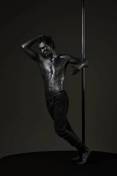 Πόλο χορού άθλημα. Αθλητικός άνδρας κάνει ακροβατικά στοιχεία στον πυλώνα. Σέξι macho με μεταλλικό δέρμα. Μυώδης άνδρας με ασημένιο σώμα τέχνη χορεύει στον πυλώνα. Προπόνηση ισχυρή χορευτής στο πόλο. Ελευθερία. — Φωτογραφία Αρχείου