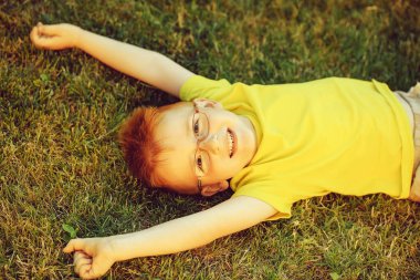 Çimenlerin üzerinde bardaklarda Kızıl saçlı erkek mutlu bebek