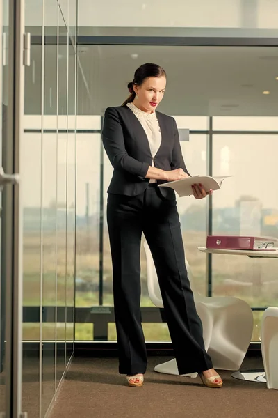 Woman in formal outfit in glass office.
