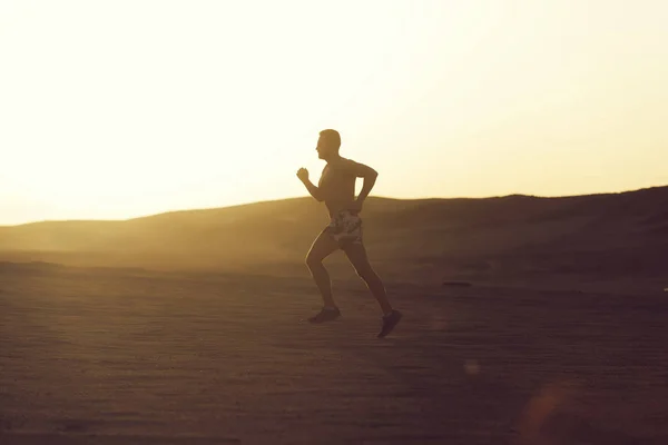 Man runner running in dune at sunset