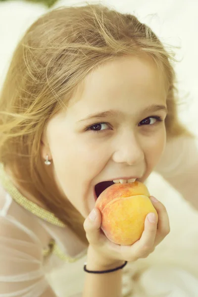 Meisje eet perzik — Stockfoto