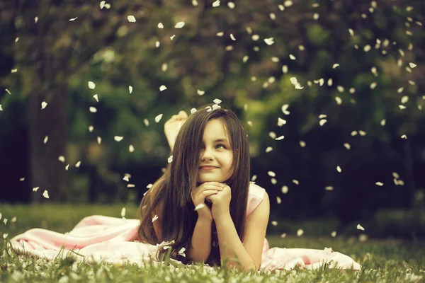 Bambina su erba verde con petali — Foto Stock