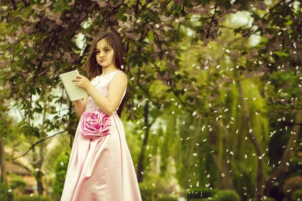 Dziewczyna w sukience z Notatnik i długopis w ogrodzie — Zdjęcie stockowe