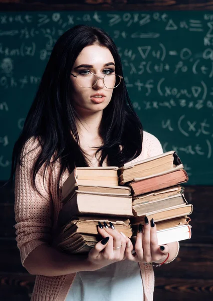 Mooie vrouwelijke student met hoopje van boeken die permanent in de klas. Brunette college meisje blokken voor examens — Stockfoto