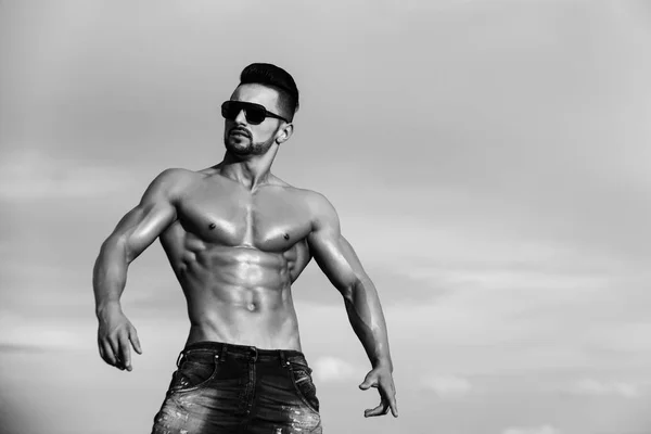 Uomo con corpo muscoloso in occhiali da sole sul cielo blu — Foto Stock