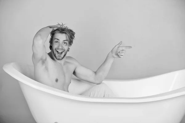 Hombre con cuerpo musculoso sentado en bañera blanca —  Fotos de Stock