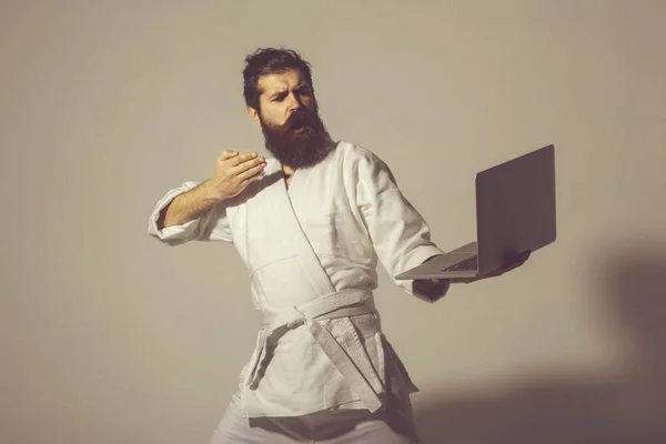 Bearded serious karate man in kimono with laptop — Stock Photo, Image
