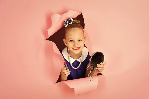 Moda y belleza en estilo pinup, infancia. Chica retro, moda, cosméticos, belleza. Maquillaje y look retro, peluquero. Niña en vestido elegante, maquillaje. Niña sostener lápiz labial y espejo . —  Fotos de Stock