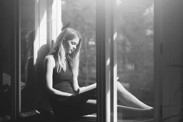 Linda chica leyendo libro en ventana abierta — Foto de Stock