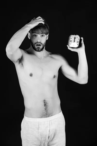 Mañana, hombre musculoso guapo con despertador sobre fondo negro — Foto de Stock