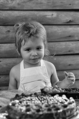 Küçük çocuk kırmızı ahududu yiyor