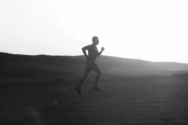 Man runner running in dune at sunset