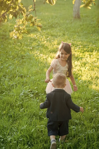 Niño y niña juegan en la hierba verde, energía —  Fotos de Stock
