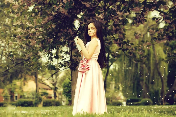 Menina de vestido com caderno e caneta no jardim — Fotografia de Stock