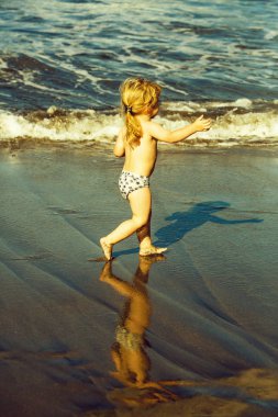 Islak kum deniz boyunca şirin neşeli bebek çocuk ishal