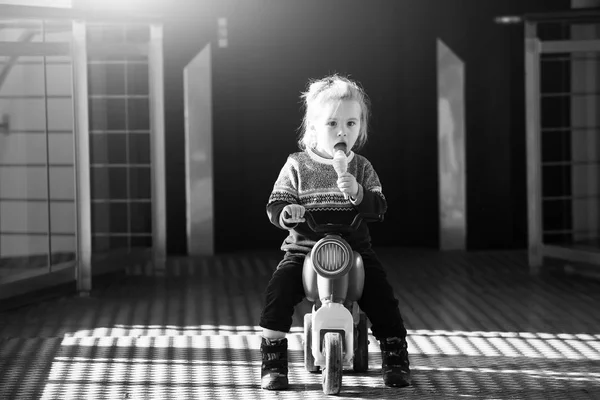 Маленький мальчик портрет едят мороженое, сидя на игрушечном велосипеде — стоковое фото