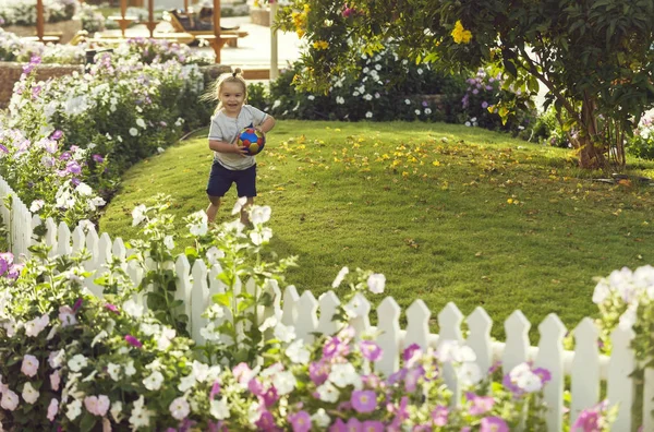 Bonito menino feliz brincando com bola na grama verde — Fotografia de Stock